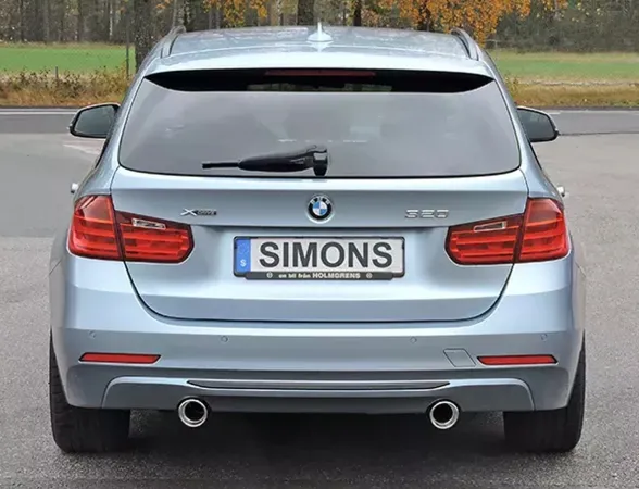 Vue arrière d'une BMW F31 320i break bleu clair avec échappement sport Duplex. Plaque Simons. Sorties d'échappement à droite et à gauche. Feux arrière et logo BMW visibles.