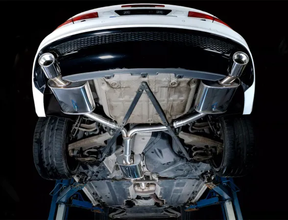 Vue de dessous d'une Audi A4 blanche sur un pont élévateur, montrant un Simons échappement sport en acier inoxydable duplex L+R avec des sorties de 1x100 mm. L'image met l'accent sur le système d'échappement, y compris les tubes et le silencieux final.